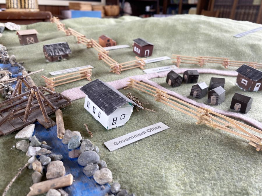 <who> Photo Credit: Andie Mollins, Local Journalism Initiative Reporter</who> A model of 150 Mile House, kept in the schoolhouse, gives an idea of what the area once looked like. The building labeled 'Government House' is the courthouse, and while it is placed on the west side of the old wagon road, Atamanenko said the courthouse has in fact always been on the east side of the road.