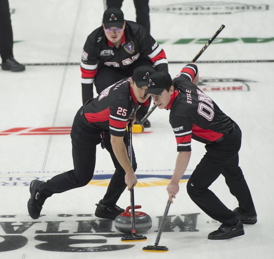 <who>Photo Credit: Curling Canada/Michael Burns</who>Scott Mitchell and Ryan Steele sweep Sam Mooibroek's stone as the Ontario skip looks on.